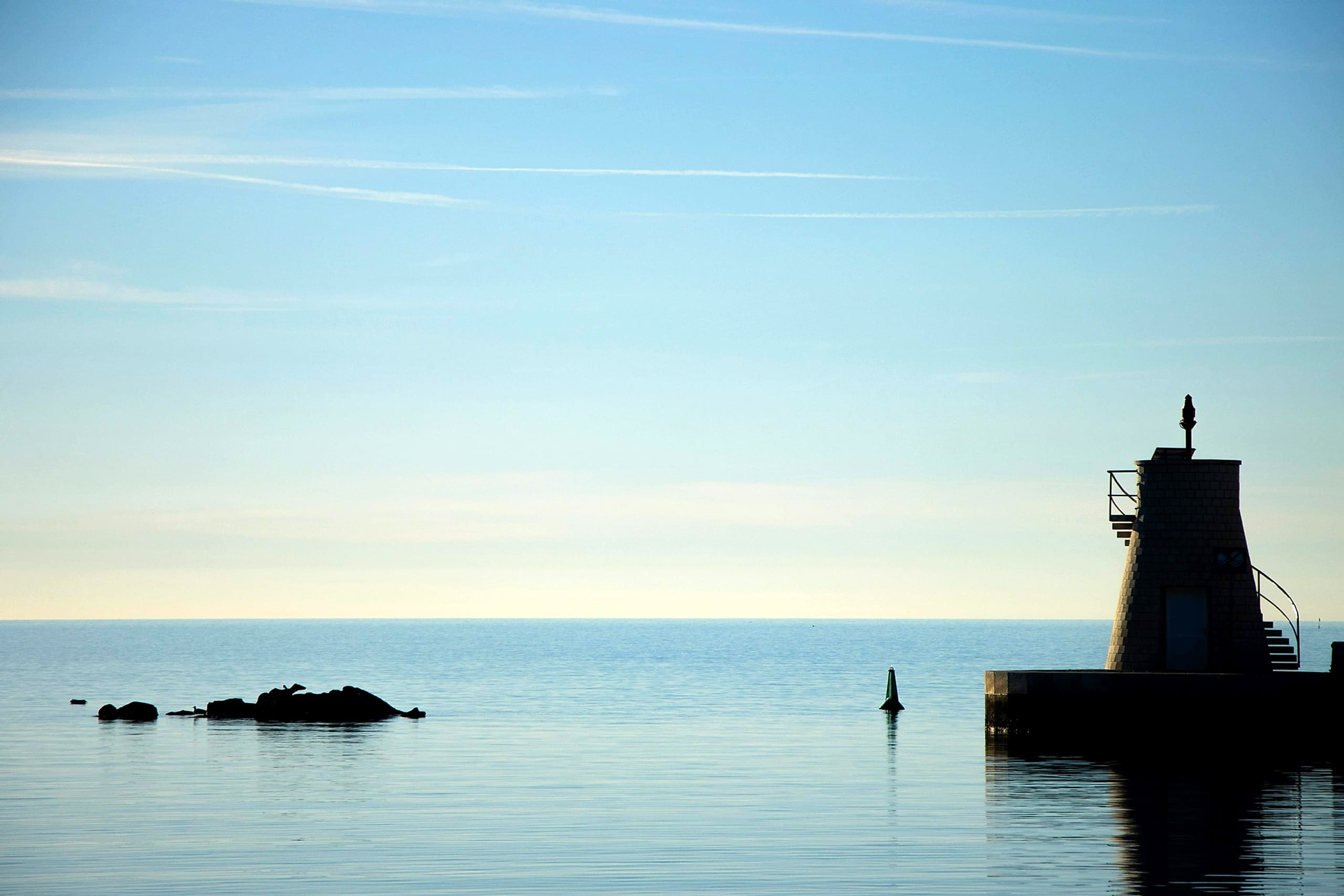 A lighthouse standing watch over calm waters at dawn